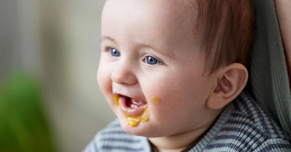 Glückliches Baby mit Essen um den Mund