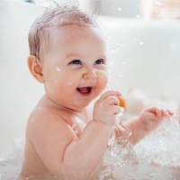 Laughing baby splashing in the bathtub